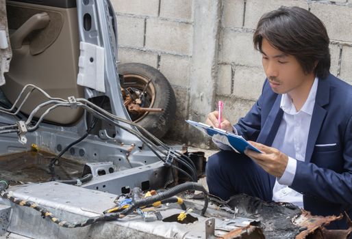 Asian Insurance Agent or Insurance Agency in Suit Inspecting Car Crash from Accident and Write Report for Insurance Claim at Outdoor Place in Serious Emotion