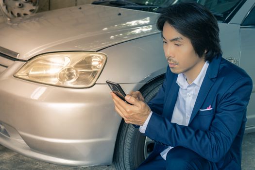 Asian Insurance Agent or Insurance Agency in Suit Touch Smartphone and Inspecting Car Crash from Accident for Claim at Outdoor Place on Wide Angle View in Vintage Tone