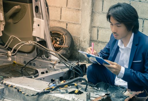 Asian Insurance Agent or Insurance Agency in Suit Inspecting Car Crash from Accident and Write Report at Side View for Insurance Claim at Outdoor Place in Serious Emotion in Vintage Tone