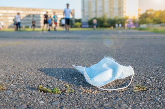 a discarded medical mask lies on the treadmill at the stadium in front of a crowd of people