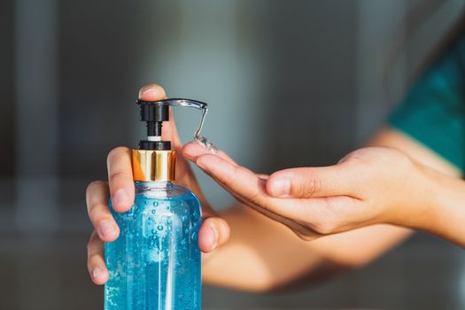 Closeup Asian woman hand using wash hand sanitizer gel pump dispenser before work over 
photo blurred of workplace while Coronavirus Network Outbreak, health care and covid19 concept