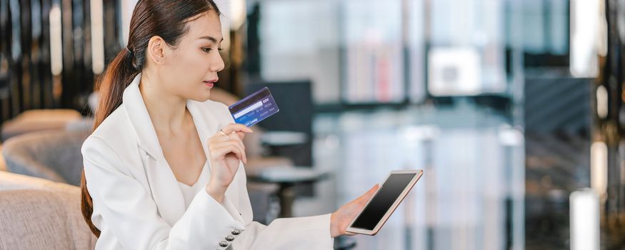 Banner, web page or cover template of Portrait Asian woman using credit card with technology tablet for online shopping in lobby or working space, technology money wallet and online payment concept