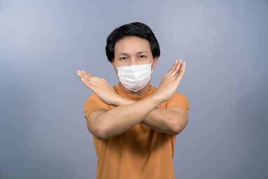 Portrait of asian male wearing face surgical mask and say no action to coronavirus  infection on blue color background, covid19 outbreak and pandemic, healthcare and protection against virus concept