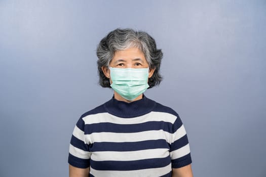 Portrait of asian old woman wearing face surgical mask on blue color background, Coronavirus pandemic, covid19 outbreak, social distancing and responsibility, protection against virus concept