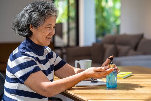Asian old man woman using hand sanitizer by pumping alcohol gel and washing before working in work from home period,coronavirus or covid19 outbreak,social distancing and responsibility