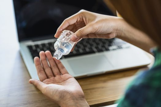 Rear view of Asian woman using hand sanitizer by alcohol gel and washing before start to work with laptop in work from home period,coronavirus or covid19 outbreak,social distancing and responsibility