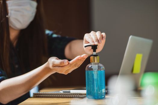 Closeup Asian female using hand sanitizer by pumping alcohol gel and washing before working with laptop in work from home period,coronavirus or covid19 outbreak,social distancing and responsibility