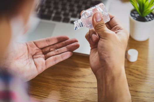 Rear view of Asian man using hand sanitizer by alcohol gel and washing before start to work with laptop in work from home period,coronavirus or covid19 outbreak,social distancing and responsibility