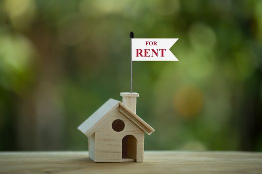 Wooden model house with paper tag on wood table background. depicts a payment for temporary use of a property owned by another owner. House for rent concept