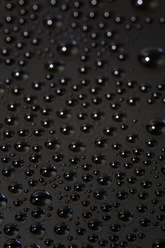 many small water drops on the black surface of cellphone hydriphobic coated glass screen, close-up with selective focus and visible subpixel rgb triads