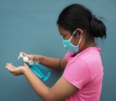 A girl wearing a protective mask And press the alcohol gel to wash your hands.