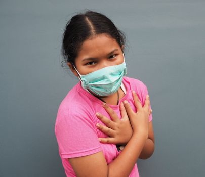 A girl wearing a protective mask While holding hands in the chest On a gray background.