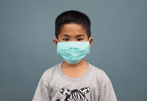 A boy wearing a protective mask on a gray background.