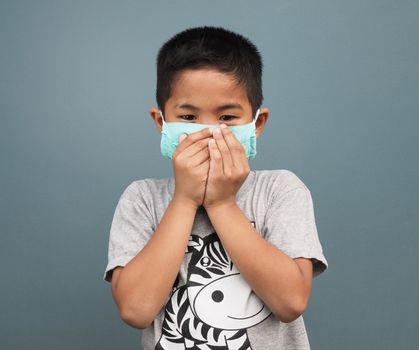 A boy wearing a protective mask While covering his mouth while coughing.