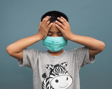 A boy wearing a protective mask And holding his hand in the head due to a lot of headaches.