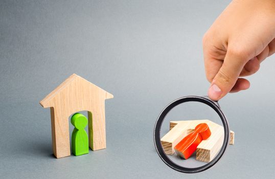 Magnifying glass is looking at a whole and ruined house with people on a dark background. bad neighbors, indifference, natural disasters and catastrophes. War conflict. Overturned wooden house