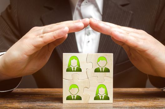 Businessman covers with hands the business team of employees. Patronage support, encouragement, privilege and financial aid. Government support smaller or local businesses. Team insurance, protection.