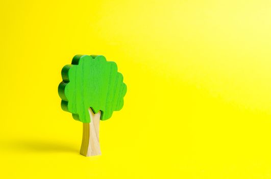 Toy wooden tree on an yellow background. Minimalism and the concept of environmental conservation. lungs of the planet. Family tree, a symbol of strength and wisdom. Illegal deforestation.