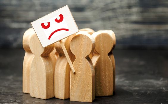 An angry mob of wooden figures of people with a poster. Social discontent and social tension, protest and disagreement. People go outside and join the protest movement. Disobedience and disobedience.