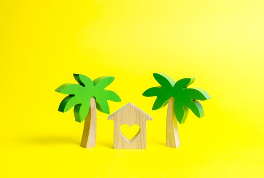 Wooden palm tree and house with hearts on an yellow background. Rental homes and properties in the resort. Romantic travel. Entertainment and relaxation. Conceptual leisure and vacation.