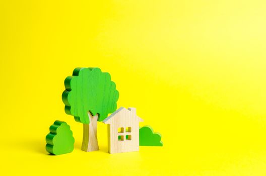 Large two-story house surrounded by bushes and trees on an yellow background. Urbanism and urban landscaping. Acquisition of affordable housing in a mortgage. Accommodation for families.