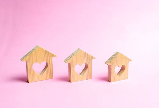 Houses with hearts inside on a pink background. The concept of finding a love nest. Affordable housing for young families and couples. Rental of houses and apartments by young people. Valentine's Day.