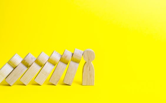 The figure of a person stops the fall of a set of figures like dominoes. Colaps dominoes. Strong leader and reliable support and loyal. business training, self-improvement, stress resistance