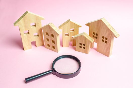 A lot of wooden houses on a pink background and a magnifying glass. The concept of finding a new home to buy or property to invest. Buying and selling real estate, investing. Romantic ancient city.
