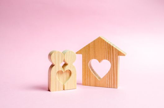 A house with a heart stands between a pair of lovers. The concept of finding a love nest. Mortgage, purchase credit. Valentine's Day. Affordable housing for couples lovers. Shared housing, new life.
