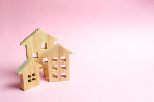 Wooden houses on a pink background. The concept of the city or town. Investing in real estate, buying a house. Management and business management, market coverage. Construction of buildings.