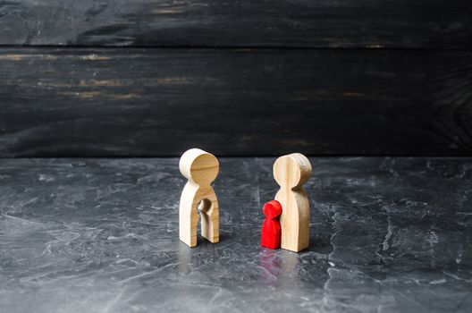 Wooden figurine of a mother with a void in the shape of a rchild looks with envy at the mother with the red child. Steal the baby. Adoption of children. futility, the desire to have children.