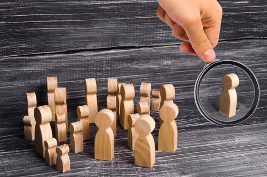 Magnifying glass is looking at the crowd of people is standing and looking at a lonely man standing. People follow the leader. Hearings, forum, rally. Expulsion from the collective. Propaganda
