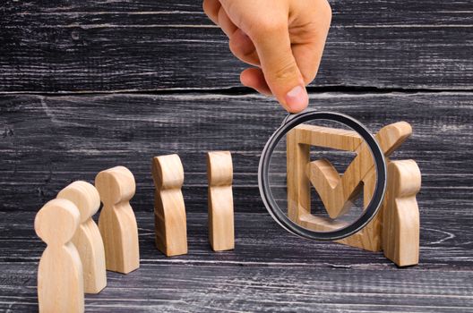 Magnifying glass is looking at the Live line of people is standing together to a tick in the box. The concept of elections and social technologies. Volunteers, parties, candidates. Human rights.