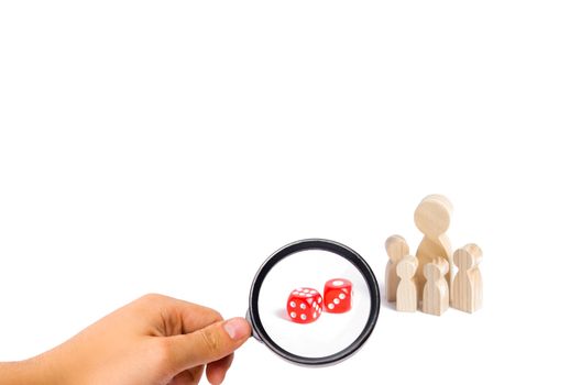 The concept of gambling, the dependence on gambling. Destruction of the family. Magnifying glass is looking at the People are standing near dice. The family stands near the dice cubes.