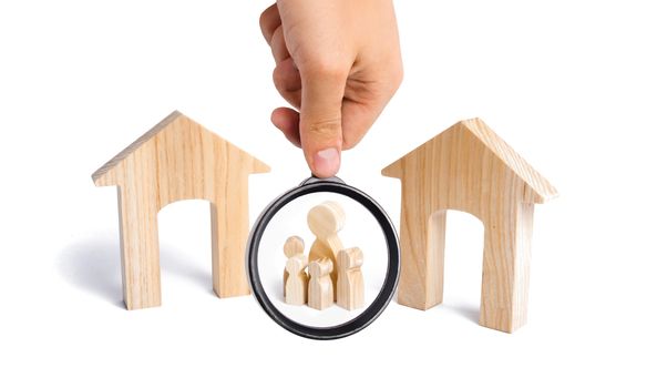 Magnifying glass is looking at the family with children stand between two houses and make a decision, they make a choice. the designation of the future family. The search for a new home.
