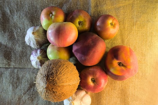 apples, peaches, garlic and coconut in the form of a bouquet - still life against a background of rough fabric