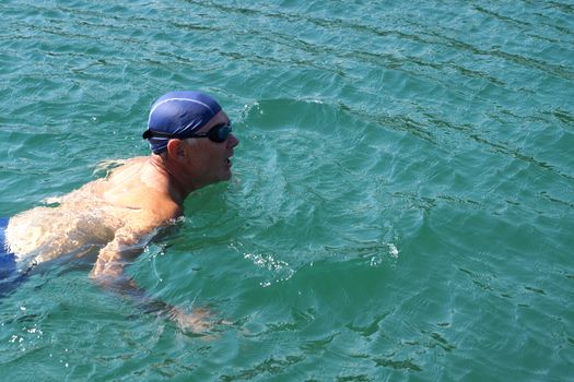 man in swimming goggles swims in the sea