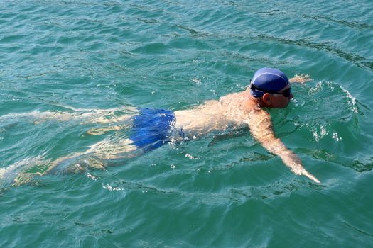 man in swimming goggles swims in the sea