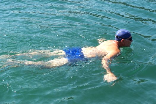 man in swimming goggles swims in the sea