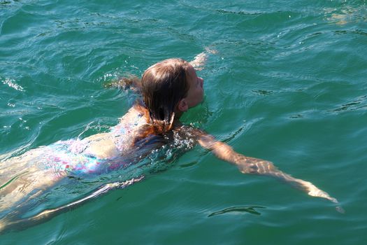 girl swims in the sea, back view