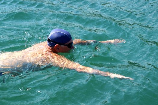 man in swimming goggles swims in the sea