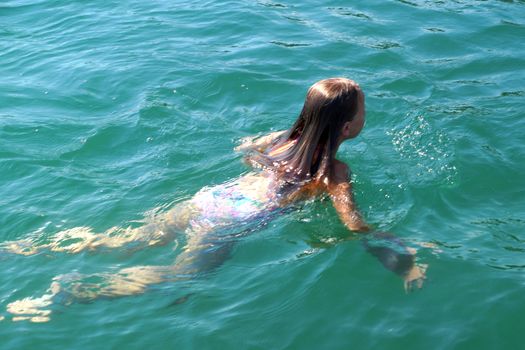 girl swims in the sea, back view