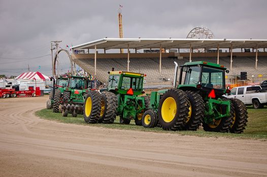 This a group of vintage tractors waiting for something to happen at a farm show.