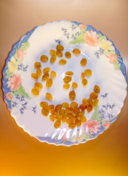 light raisins scattered on a beautiful white plate with painted flowers