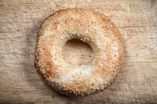 Sesame seeded bagel bread roll isolated on a wooden chopping board stock photo