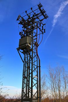 Electric antenna and communication transmitter tower in a european landscape against a blue sky