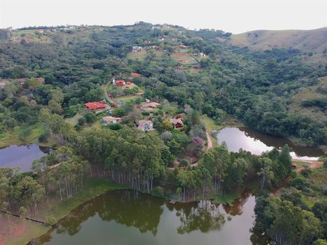 Aerial View of green scenic forest and land in the mountain in tropical country. Aerial view of forest to make with farm field and villa. Green area in the forest with lake