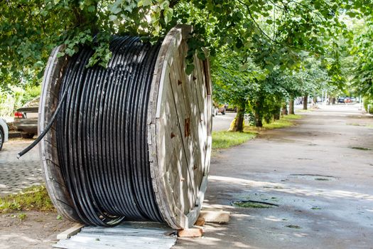 large wooden industrial reel with cable in city street on sunny summer day