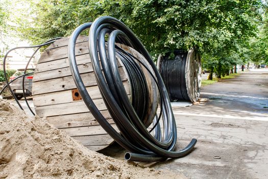 two large wooden industrial reels with cable in city street on sunny summer day