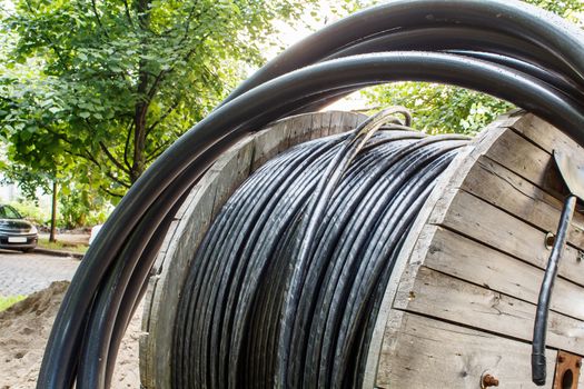 large wooden industrial reel with cable in city street on sunny summer day